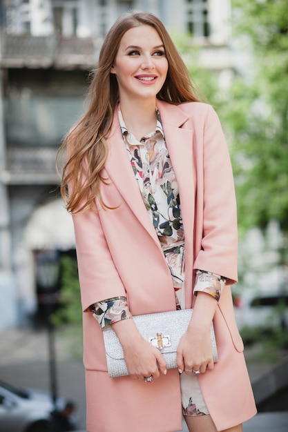 Lindo retrato de mujer sonriente con estilo atractivo caminando calle de la ciudad en abrigo rosa