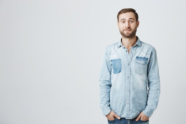 Lindo tímido novio barbudo en camisa vaquera, sonriendo