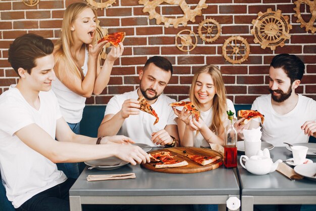 Lindos amigos en una cafetería comiendo una pizza