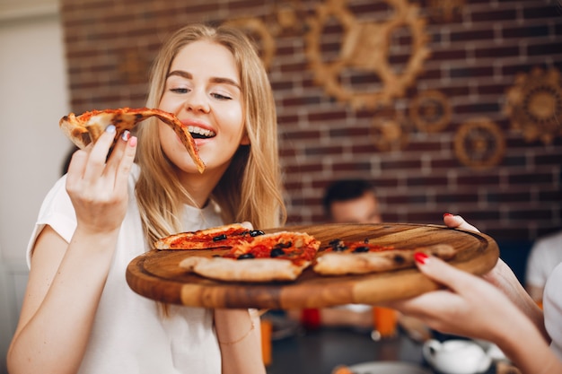 Foto gratuita lindos amigos en una cafetería comiendo una pizza