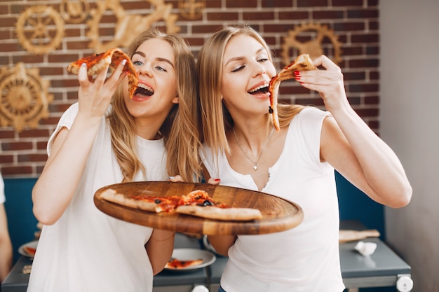 Lindos amigos en una cafetería comiendo una pizza