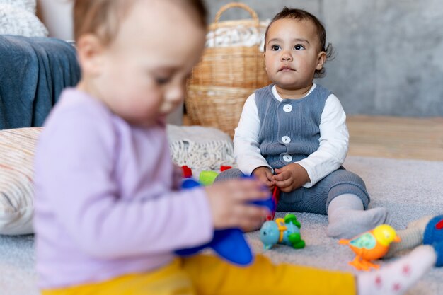 Lindos bebés jugando en el suelo con juguetes