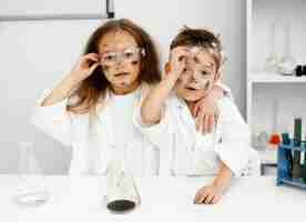 Foto gratuita lindos científicos de niña y niño en el laboratorio con tubos de ensayo y experimento fallido