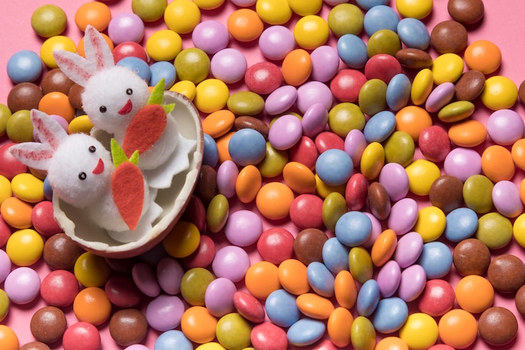 Foto gratuito lindos dos conejitos dentro del huevo de pascua roto sobre los caramelos de gemas de colores