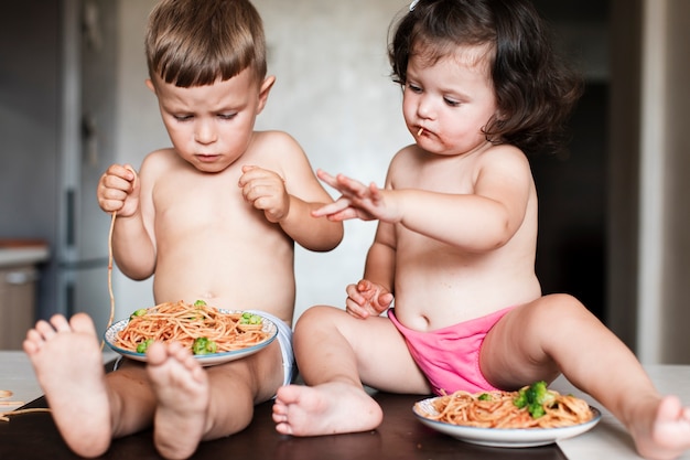 Lindos hermanos jóvenes jugando con comida