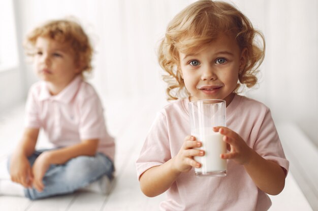 Lindos niños bebiendo leche en casa