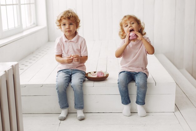 Lindos niños comiendo galletas en casa