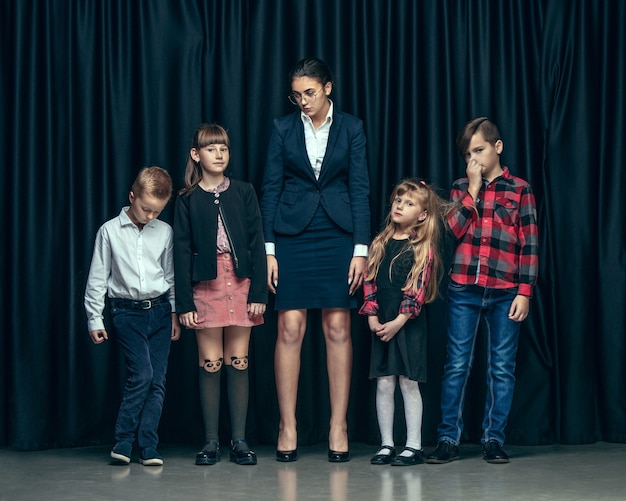 Lindos niños con estilo en estudio oscuro. Las hermosas adolescentes y el niño parados juntos