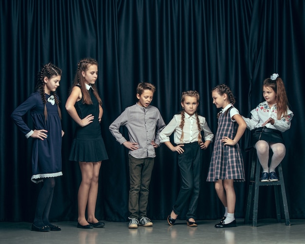 Lindos niños con estilo en estudio oscuro. hermosas chicas adolescentes y un niño parados juntos