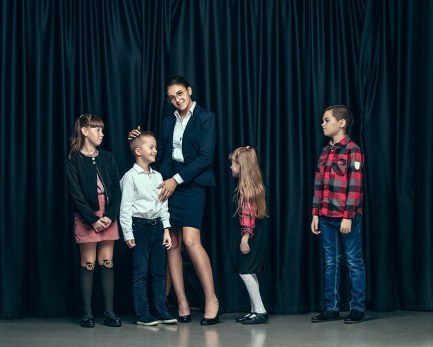 Lindos niños con estilo sobre fondo oscuro de estudio. Las hermosas adolescentes y el niño parados juntos