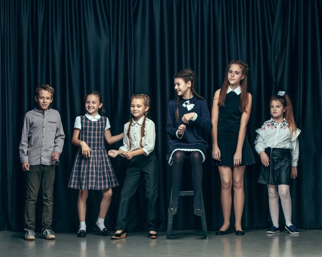 Lindos niños con estilo sobre fondo oscuro de estudio. Las hermosas adolescentes y el niño parados juntos