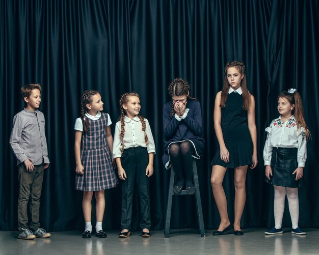 Lindos niños con estilo sobre fondo oscuro de estudio. Las hermosas adolescentes y el niño parados juntos