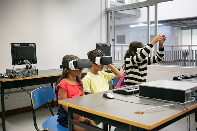 Foto gratuita lindos niños multiétnicos aprendiendo a usar gafas de realidad virtual