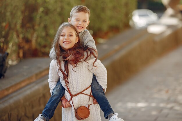 Lindos niños pequeños con bolsa de compras en una ciudad