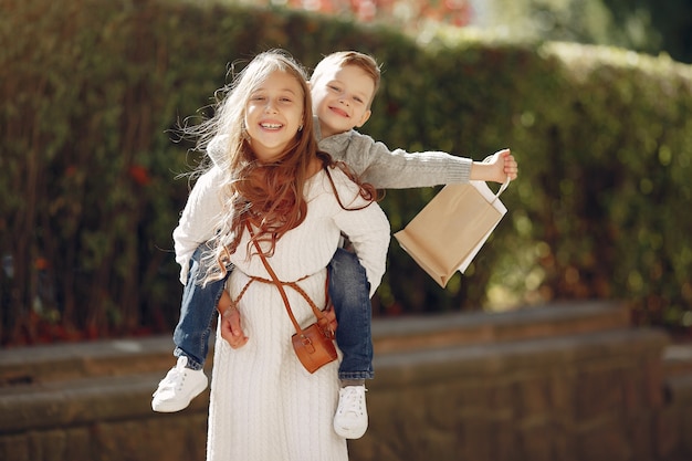 Lindos niños pequeños con bolsa de compras en una ciudad