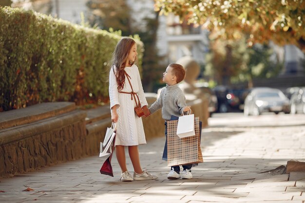 Lindos niños pequeños con bolsa de compras en una ciudad