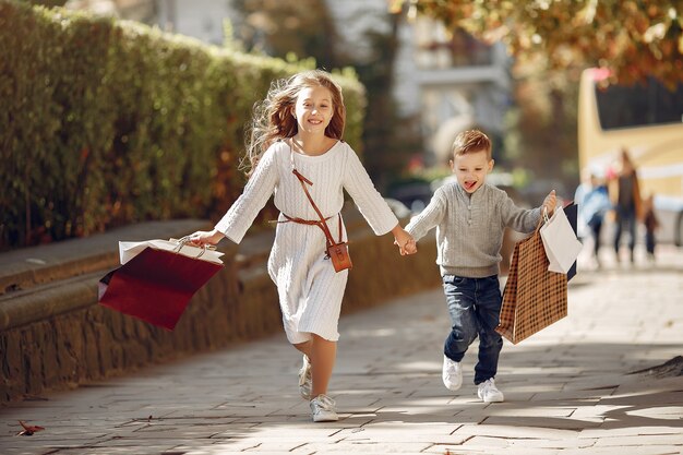 Lindos niños pequeños con bolsa de compras en una ciudad