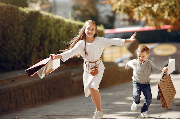 Lindos niños pequeños con bolsa de compras en una ciudad