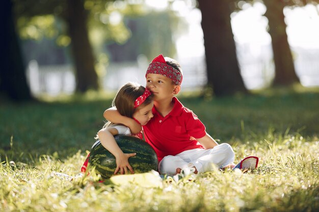 Lindos niños pequeños con sandías en un parque