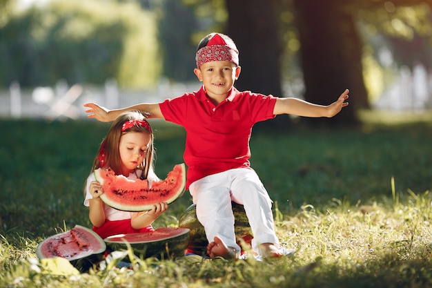 Lindos niños pequeños con sandías en un parque