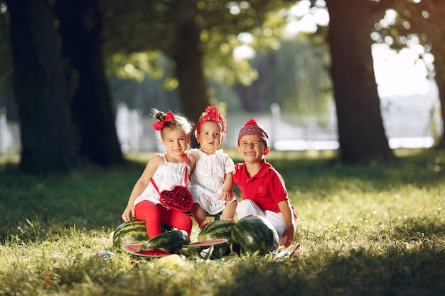 Lindos niños pequeños con sandías en un parque