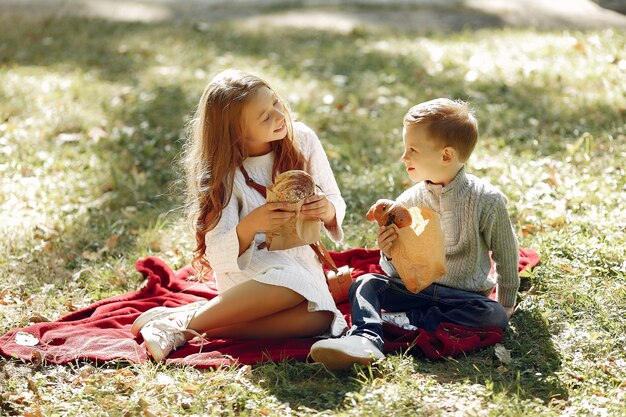 Lindos niños pequeños sentados en un parque con pan