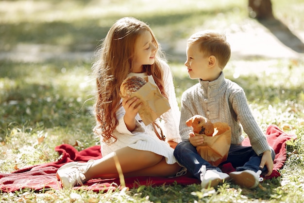 Lindos niños pequeños sentados en un parque con pan