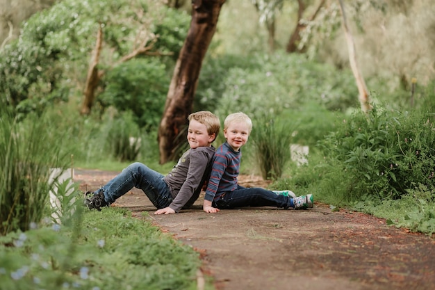 Lindos niños rubios sentados en el suelo en un parque y jugando