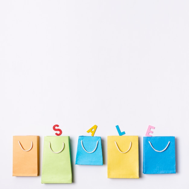 Foto gratuita línea de bolsas de papel de colores con concepto de texto de venta