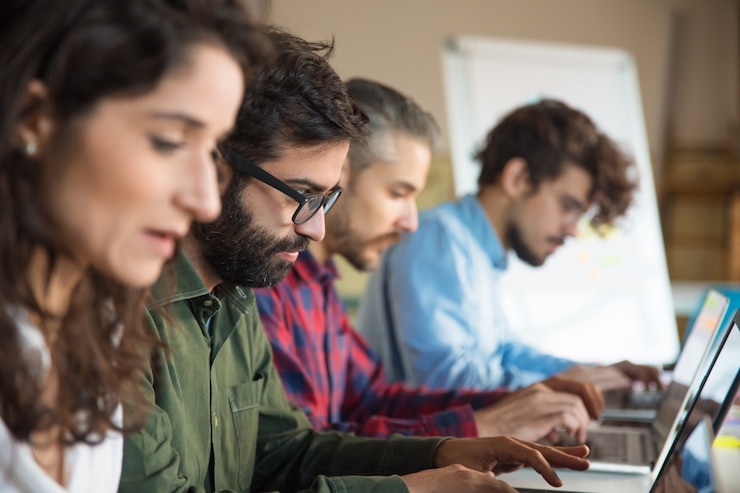 Foto gratuito línea de compañeros de trabajo que usan computadoras portátiles en la sala de entrenamiento o clase