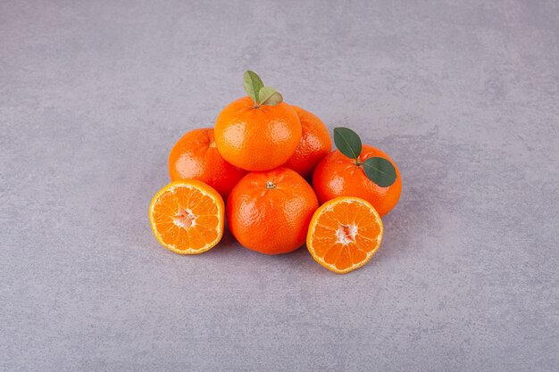 Línea de frutos dulces mandarina con hojas colocadas sobre una piedra.