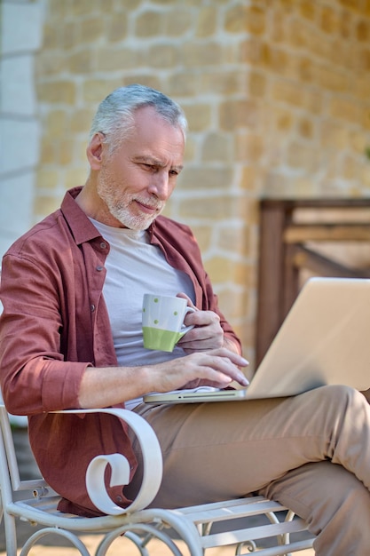 Foto gratuita en línea. un hombre con camisa burdeos con una computadora portátil en las manos.