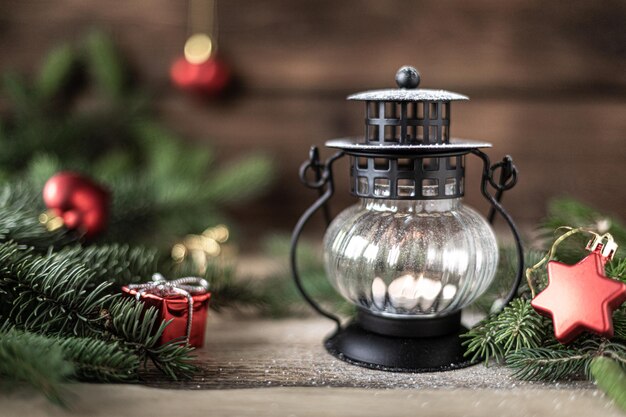Linterna navideña con velas y ramas de abeto con conos en una mesa de madera