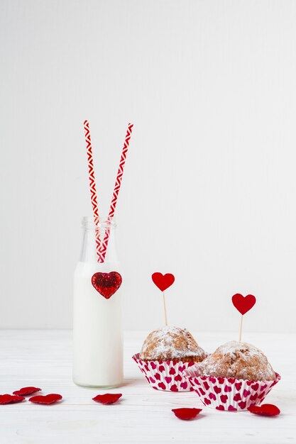 Líquido blanco en botella con tubos cerca de tortas con corazón en varitas