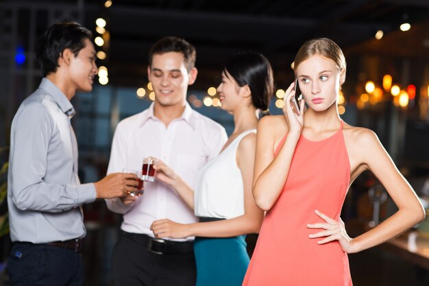 Llamada de la mujer en el teléfono y amigos en el partido