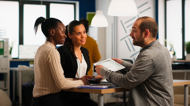 Lluvia de ideas de trabajo en equipo de diversidad de inicio sentado en el escritorio en la oficina moderna, planificación de la estrategia empresarial con tableta buscando soluciones de gestión. Equipo de empresa de trabajo de empresarios multiétnicos