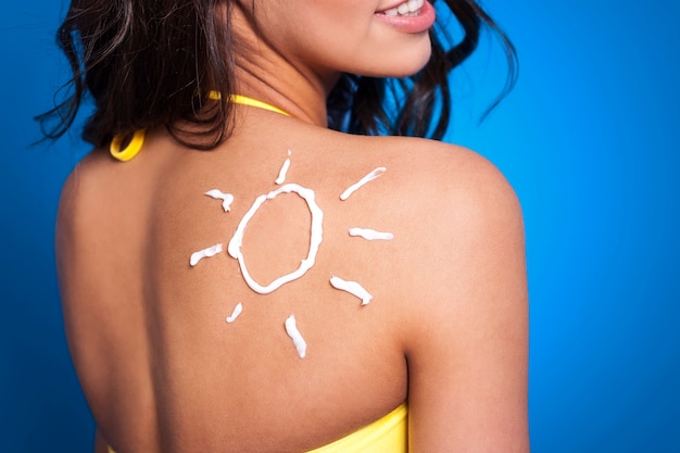 Loción bronceadora en el brazo de la mujer en forma de sol