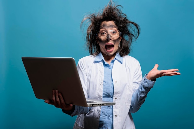 Foto gratuita loco científico en pánico gritando de pánico después de la explosión del laboratorio mientras tenía una computadora portátil. químico loco y asustado con cara sucia y cabello desordenado gritando de miedo después de un experimento químico fallido.