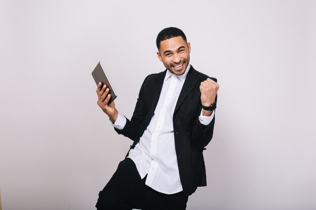 Lograr grandes resultados en el trabajo, éxito en la carrera de un joven apuesto con camisa blanca, chaqueta negra que expresa felicidad. Hombre de negocios elegante, moderno, alegre, sonriente.