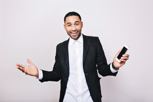 Logro grandes resultados en el trabajo, éxito en la carrera de un joven apuesto con camisa blanca, chaqueta negra que expresa felicidad. Hombre de negocios con estilo, alegría, sonrisa, positividad.