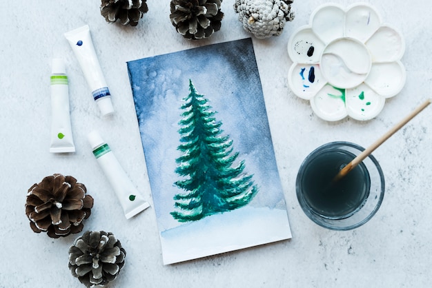 Lona de árbol de navidad dibujada con piñas; Tubos de color y pincel sobre fondo texturizado.