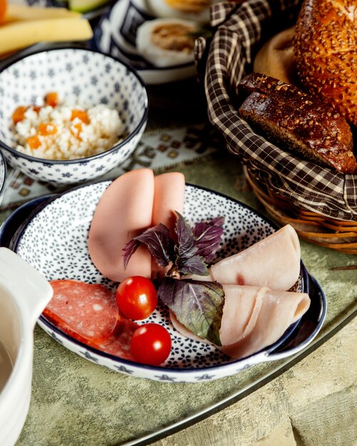 Lonchas de jamón y salchicha con cesta de pan