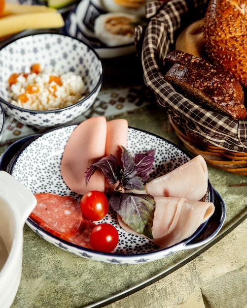 Lonchas de jamón y salchicha con cesta de pan