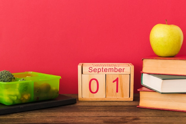 Lonchera y calendario cerca de frutas y libros