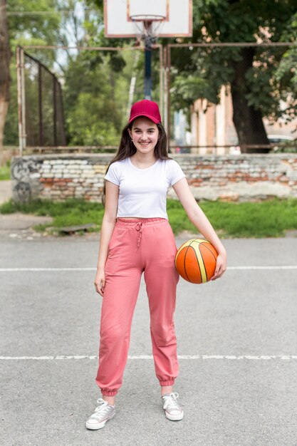 Long shot joven sosteniendo una pelota de baloncesto