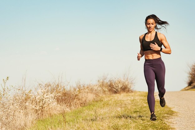 Longitud total de atleta femenina determinada corriendo mientras hace ejercicio en la naturaleza Espacio de copia