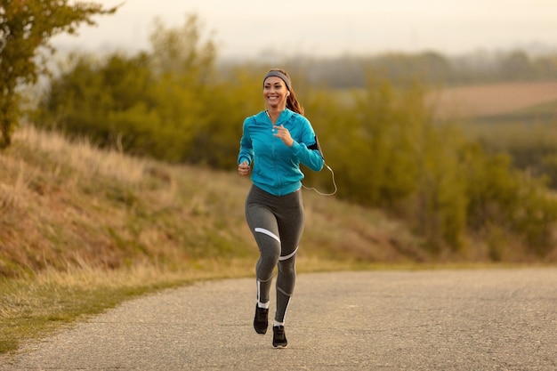 Longitud total de deportista feliz trotando en la carretera por la mañana Copiar espacio