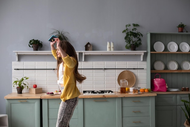 Longitud total de hermosa morena con ropa de moda y tacones bailando en la cocina Sintiéndose feliz por la mañana Interior moderno