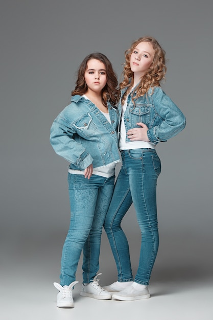 Longitud total de joven delgada femenina en jeans de mezclilla sobre fondo gris