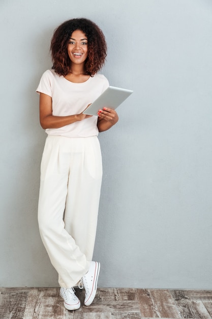 Longitud total de una mujer afroamericana sonriente casual de pie